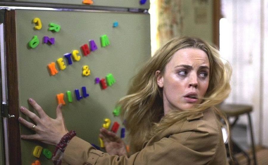 Melissa George looking scared holding on to the fridge with magnets spelling out ‘Ketcham and Kill Em’