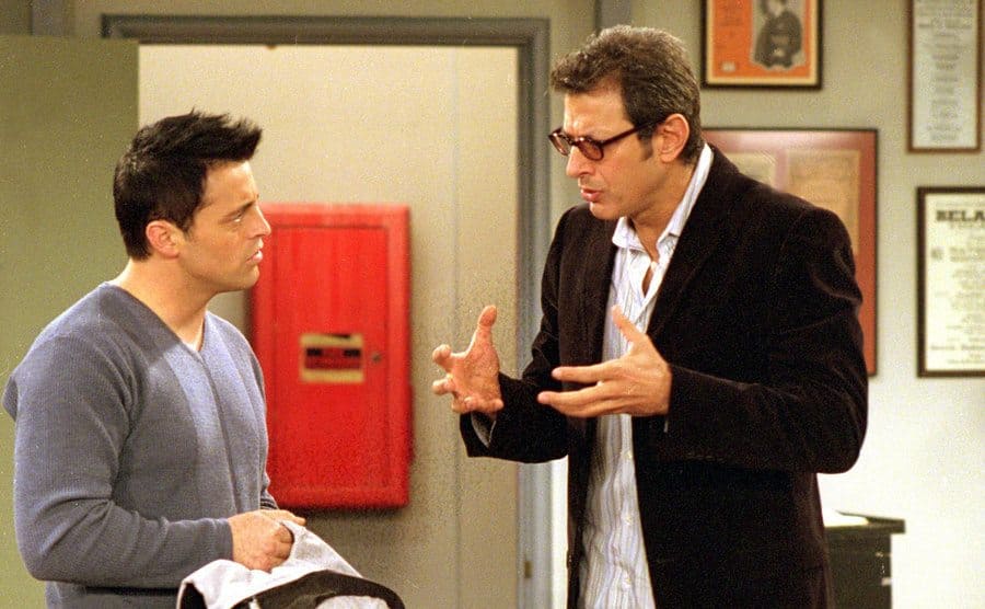 Matt LeBlanc y Jeff Goldblum dialogando de pie en una habitación