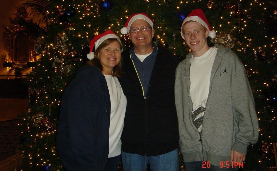 Bryce Laspisa poses with his parents in front of a Christmas tree. 