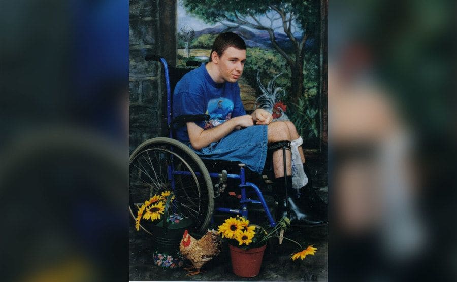 Martin is sitting in his wheelchair in the garden. 