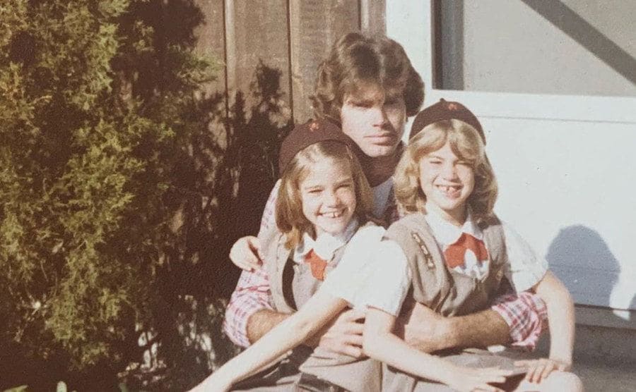 Denise Richards is dressed in a girl scout uniform, poses for a picture with her father and sister. 
