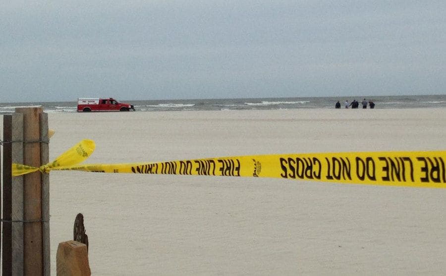 Police tape blocks the entrance to the beach. 