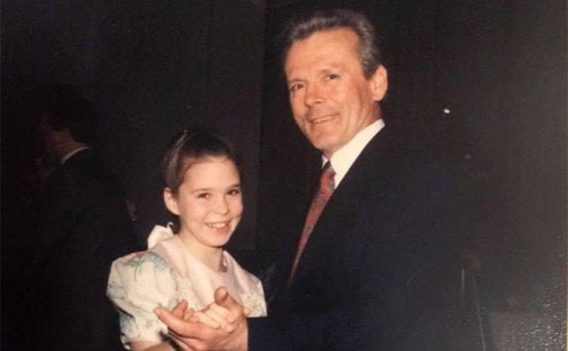 A young Maura dancing with her father at an event. 