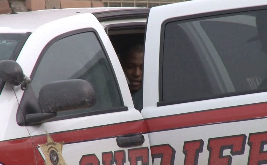 Michael Beard is placed in a police car. 