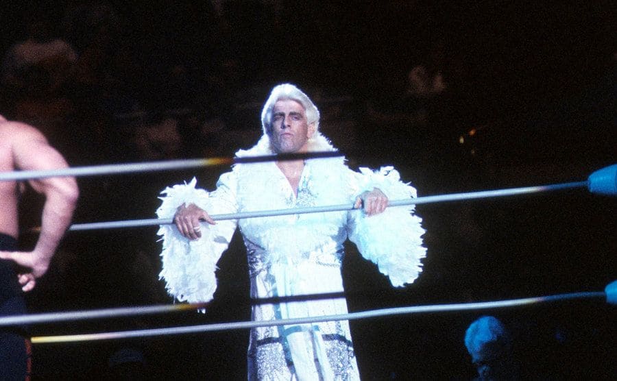 Rick Flair steps into the ring dressed in white silk and feathers circa 1988.