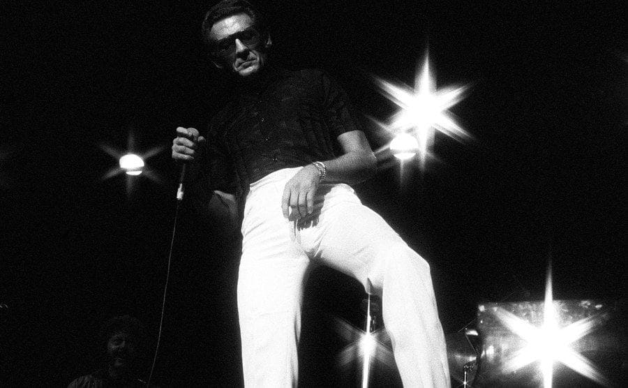 Rock 'N' Roll and country star Jerry Lee Lewis perform on a dark stage and flashy lights.