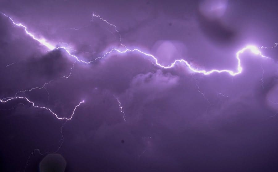 Lightening strikes in a dark purple sky.