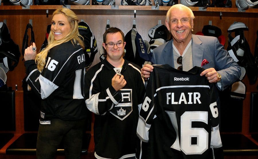 Ric Flair next to Los Angeles son coach and Charlotte, holding a Kings jersey shirt number 16 “Flair” at the back.