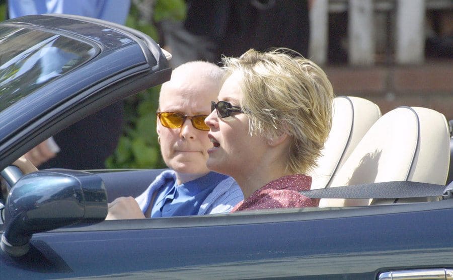 Sharon Stone is driving her car accompanied by a friend.