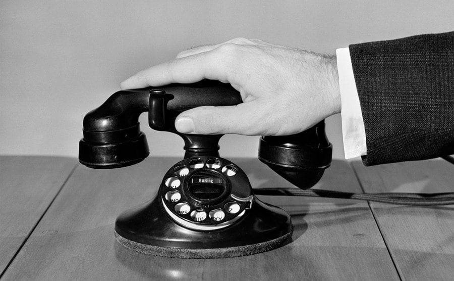 A vintage photo of a man hanging up a phone. 