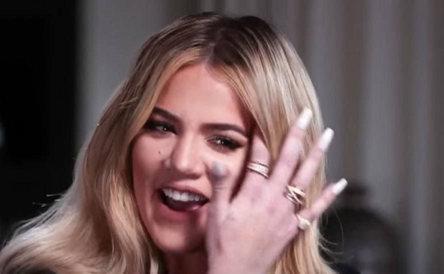 Khloe is smiling at the interview while flipping her hair.