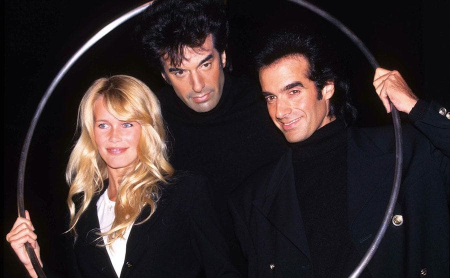 Claudia Schiffer and David Copperfield are posing and holding a hula-hoop.