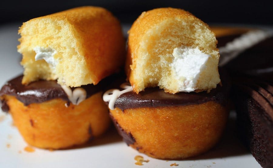 A split open Twinkie is placed on top of two Hostess cupcakes. 