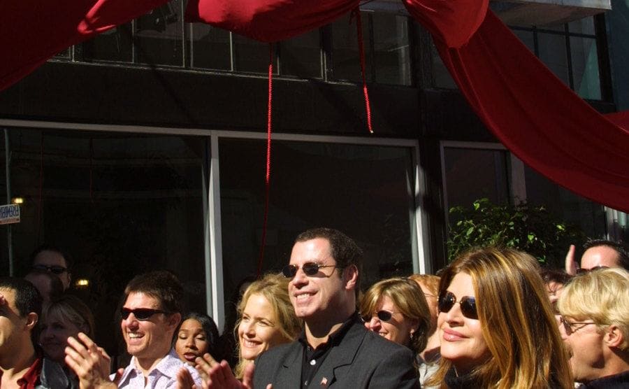 Tom Cruise, Kelly Preston, John Travolta, and Kirstie Alley listen to Jenna Elfman speak at the opening of the Church of Scientology.