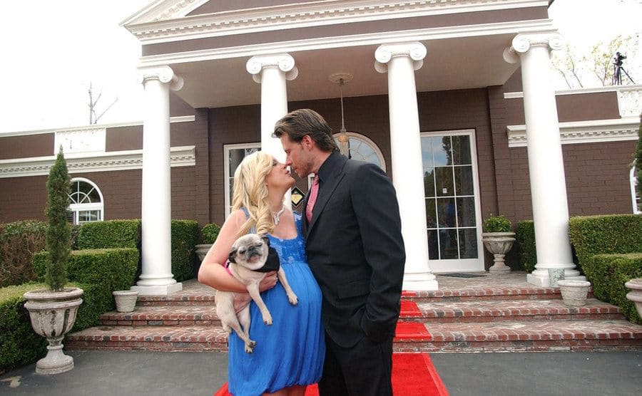 Tori Spelling and Dean McDermott pose with their dog at the entrance of Chateau La Rue. 
