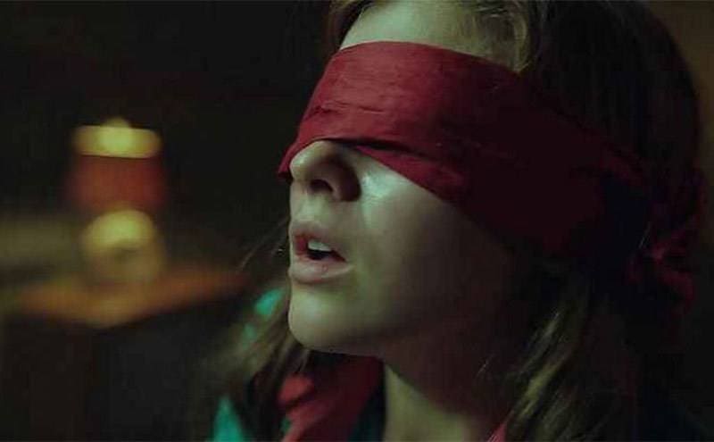 Katie Douglas, as Lisa McVey, sits blindfolded in the passenger seat. 