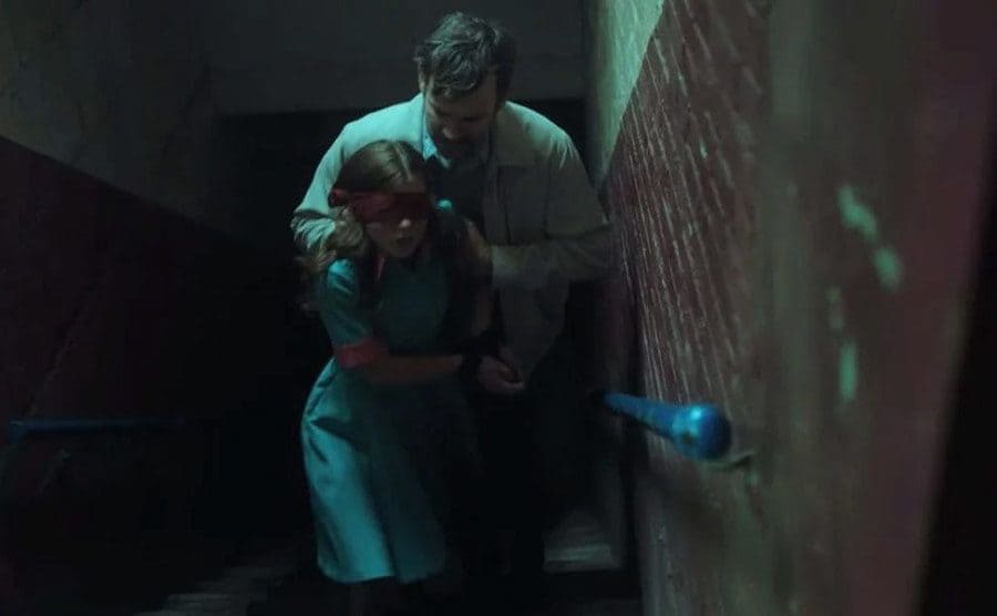 Douglas, as McVey, is being forced up the stairs by a man. 