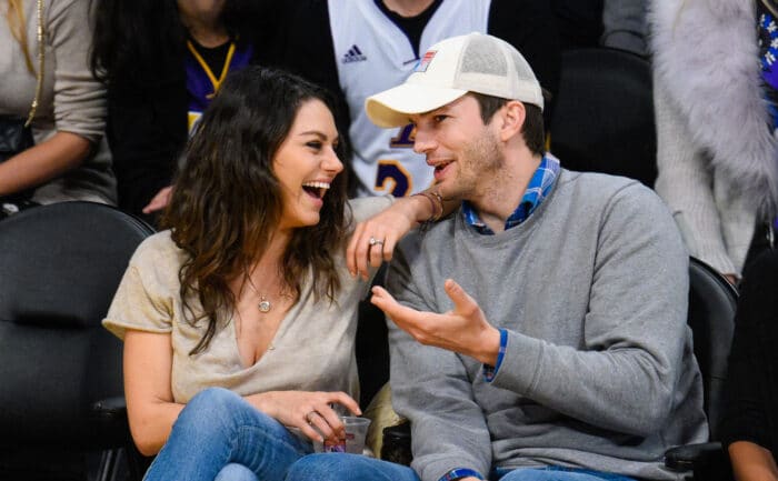 Mila Kunis and Ashton Kutcher are having a laugh at a basketball game. 