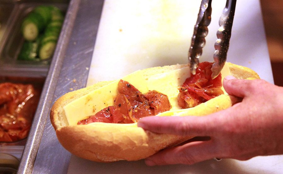 Adding roasted tomatoes to mozzarella and artichoke aioli sandwich. 