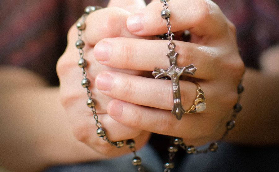 Two hands are holding a rosary. 