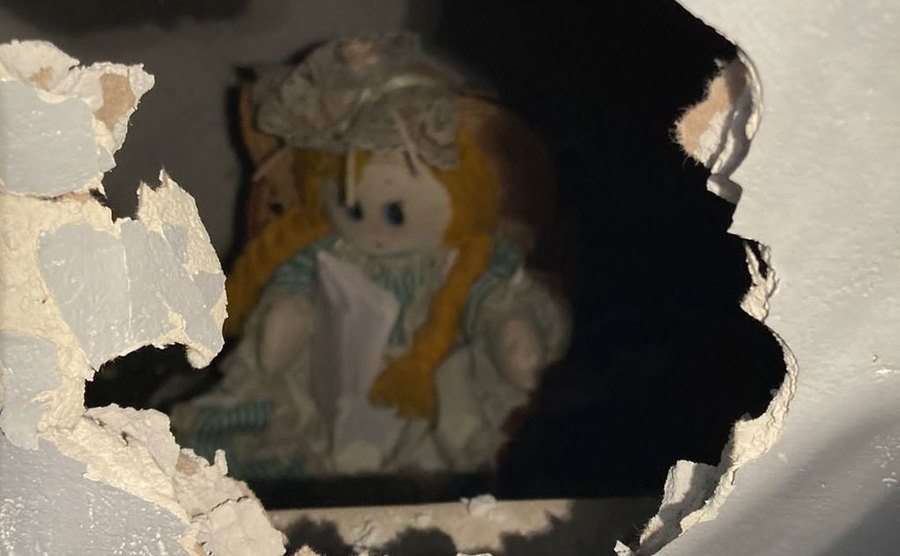 A hole in the wall shoes a doll hidden behind it. 