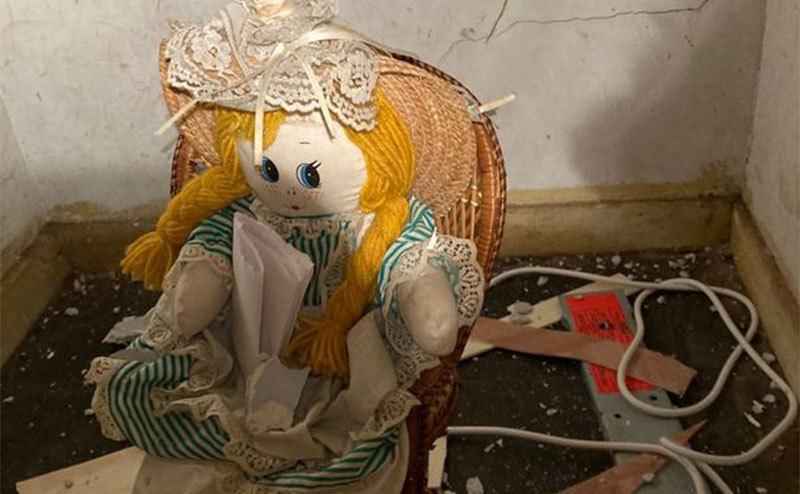 A closer look at the doll, she sits in a chair, holding a note. 