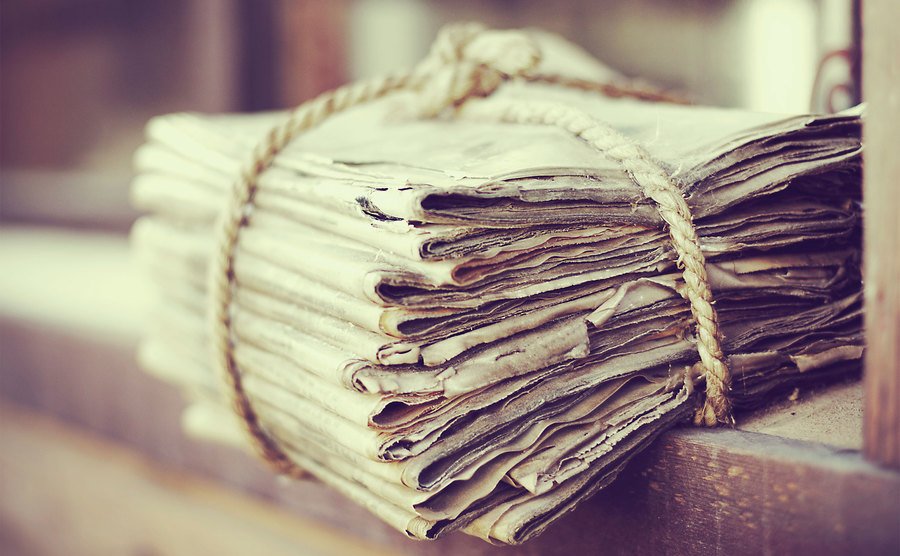 A pile of old newspapers is tied with a string.