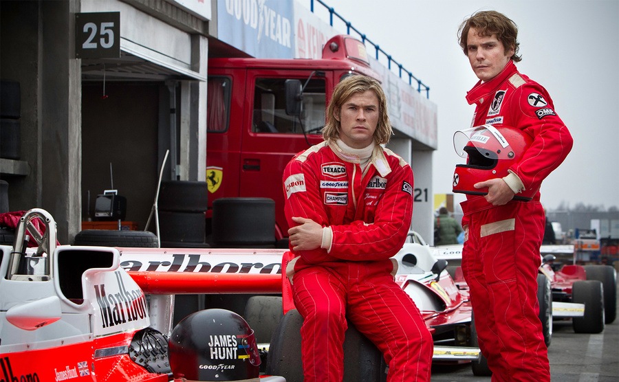 Chris Hemsworth and Daniel Brühl pose beside their race cars. 