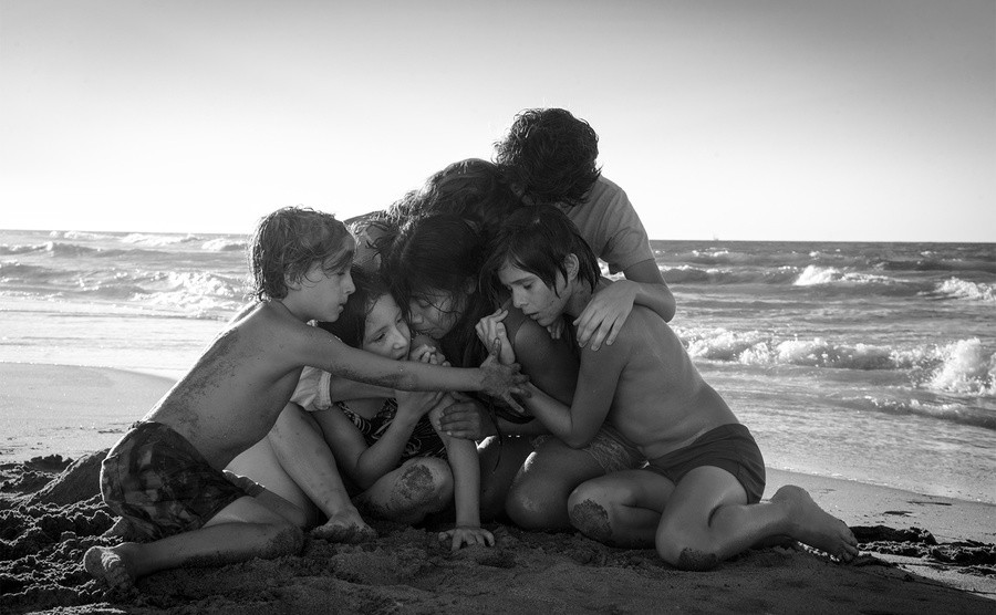 The cast of Roma embraces on the beach. 