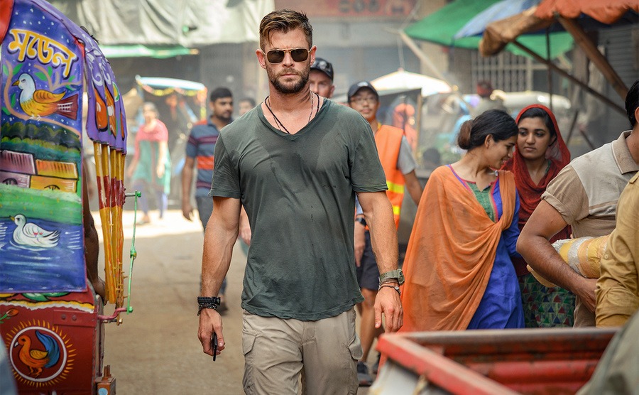 Chris Hemsworth, as Tyler Rake, walks through a street market. 