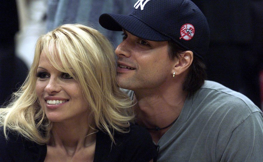 Pamela Anderson und Marcus Schenkenberg lächeln und schauen sich ein NBA-Spiel an