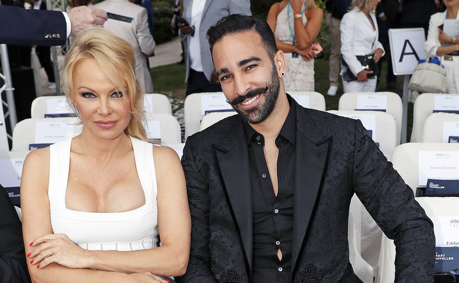 Pamela Anderson und Adil Rami sitzen in der ersten Reihe bei einer Outdoor-Modenschau