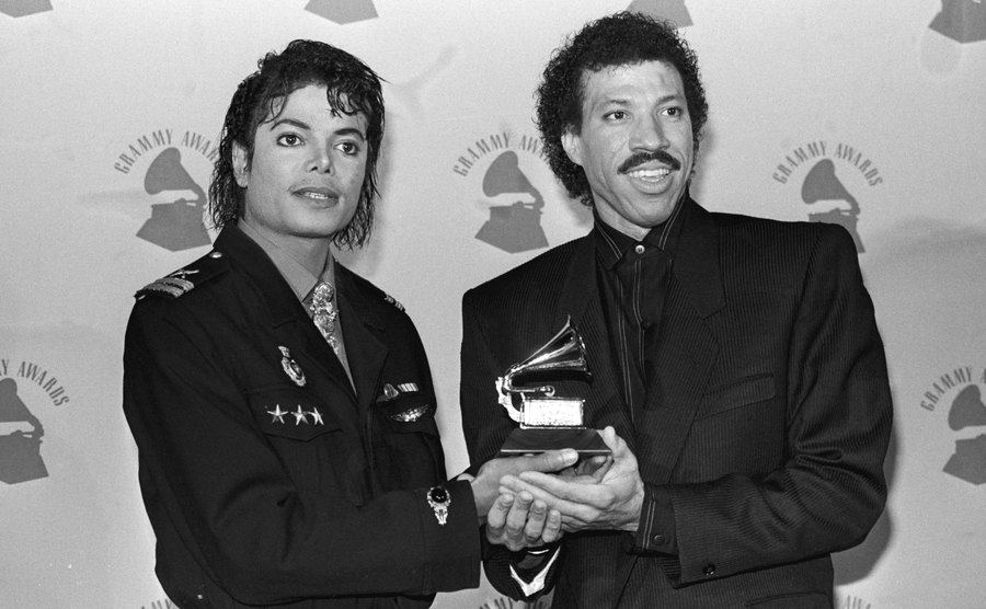 Michael Jackson and Lionel Ritchie pose, holding their award.