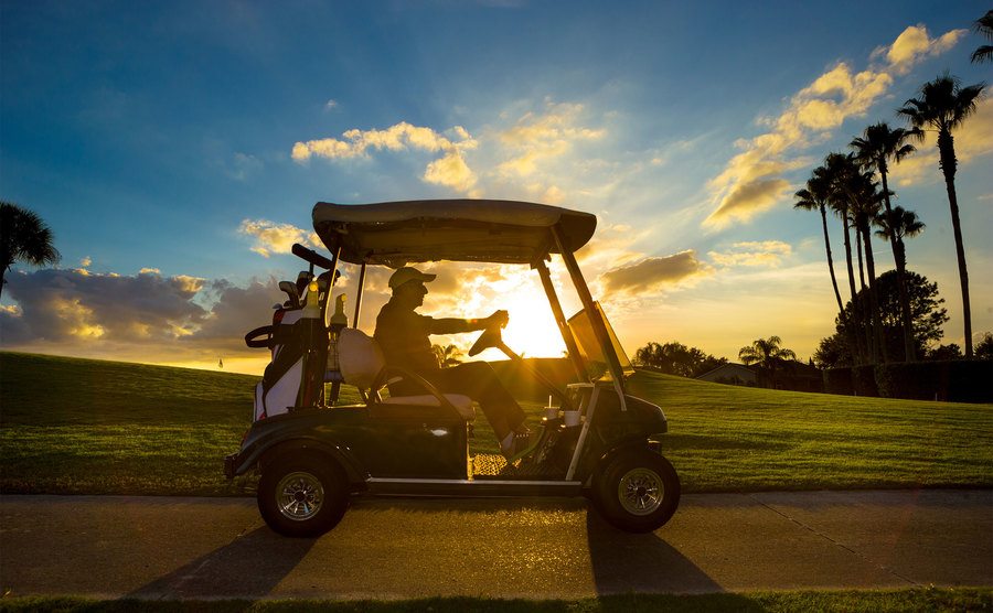 Ein älterer Mann fährt einen Golf Cart bei Sonnenaufgang.