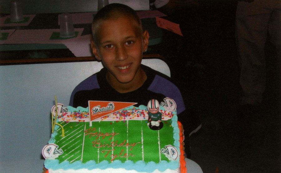 O pequeno Tyler Hadley posa com seu bolo de aniversário.