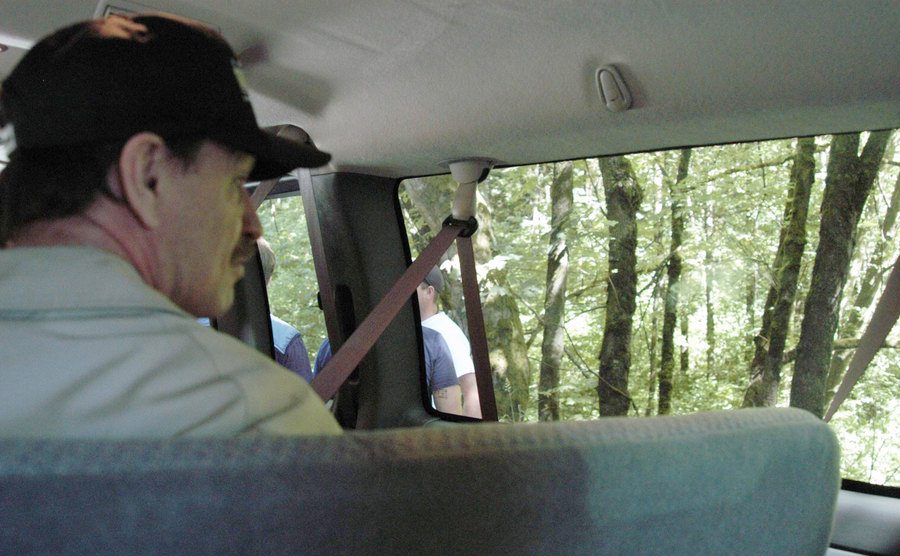 Gary leads investigators to one of his crime scenes in a woody area.
