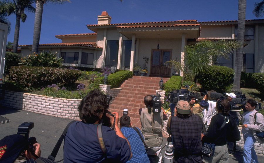 The press waits outside the cult’s house.