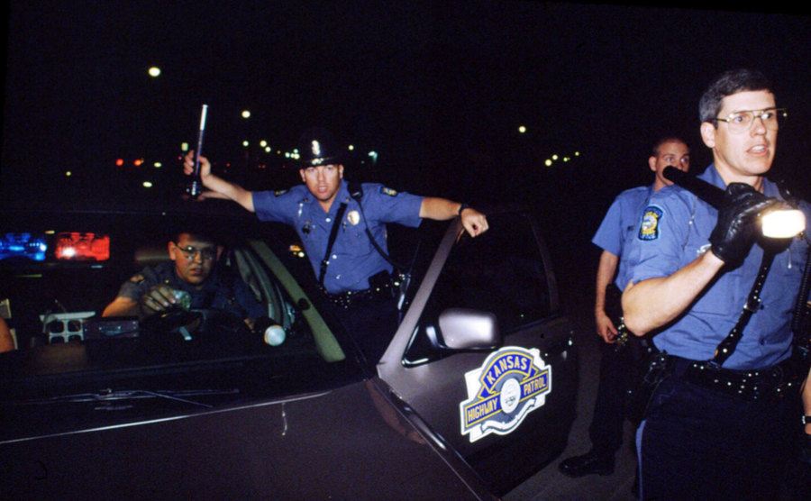 An image of John Walsh giving a speech / A picture of police officers on duty at night.