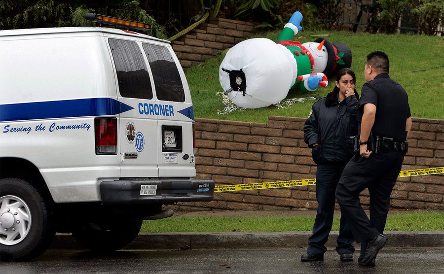 Coroner and police stand outside the home decorated for Christmas. 