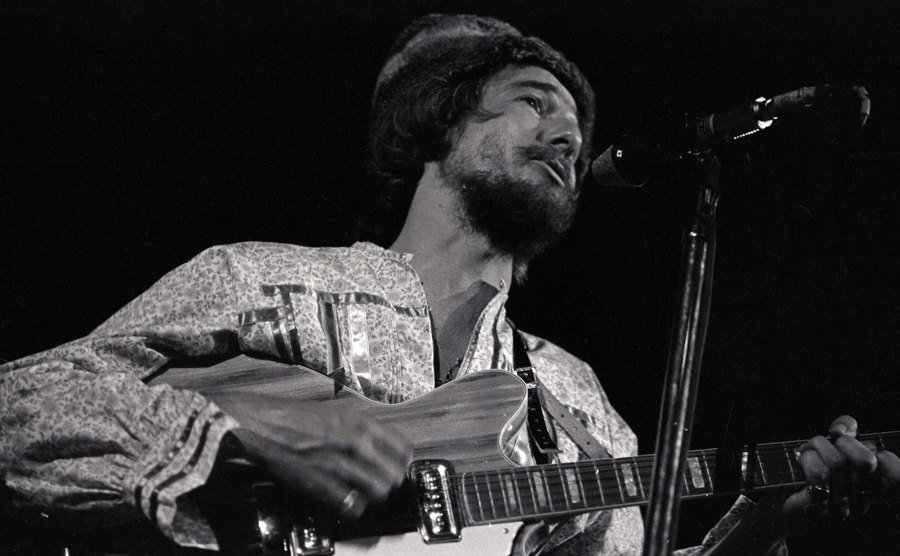 An image of John Phillips performing on stage.