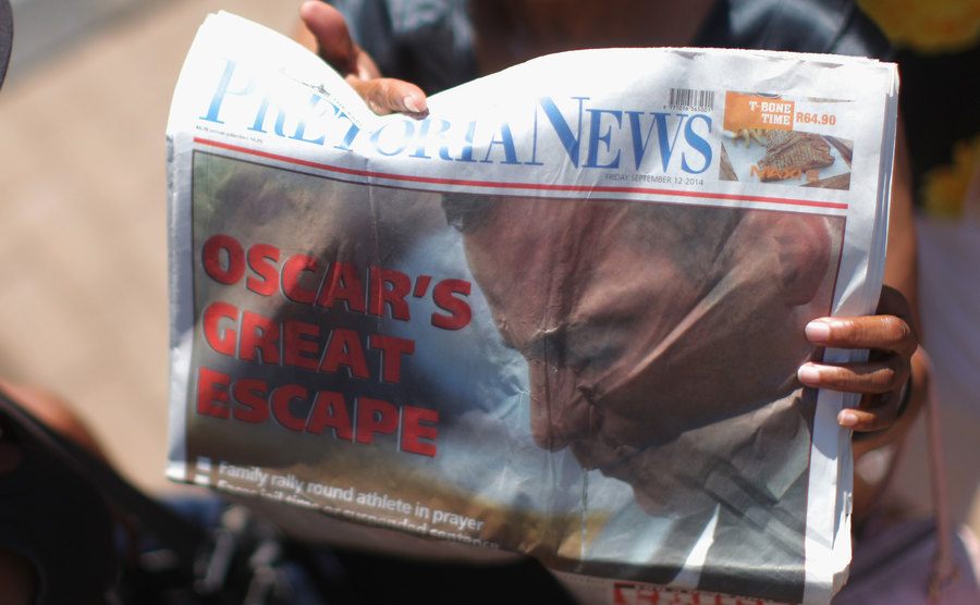 A woman holds a newspaper headlining the Oscar Pistorius court case.