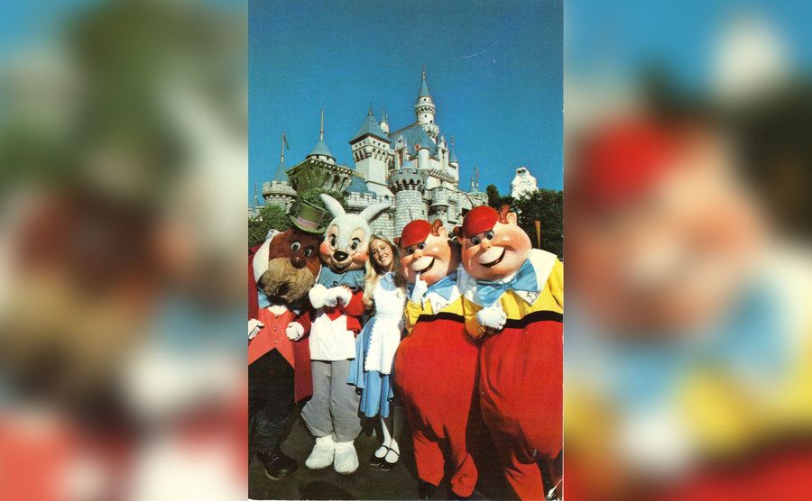 Pfeiffer, as Alice, poses with cast members at Disneyland. 