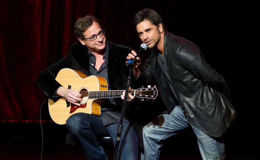 A picture of Saget and Stamos performing together on stage.
