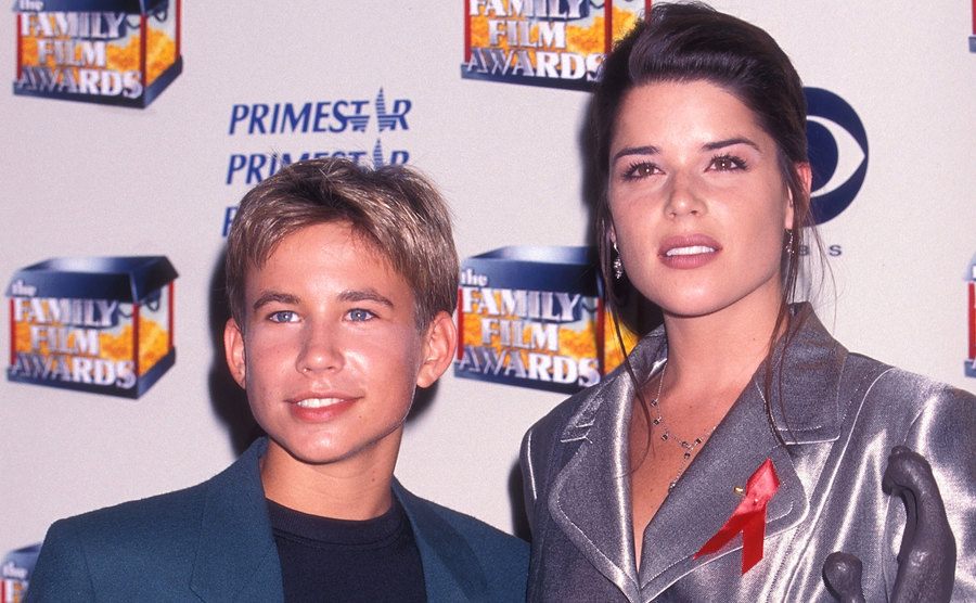 A photo of Jonathan Taylor Thomas and Neve Campbell posing for the press.
