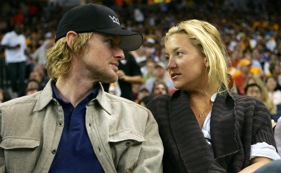 Owen Wilson and Kate Hudson talk during a basketball game. 