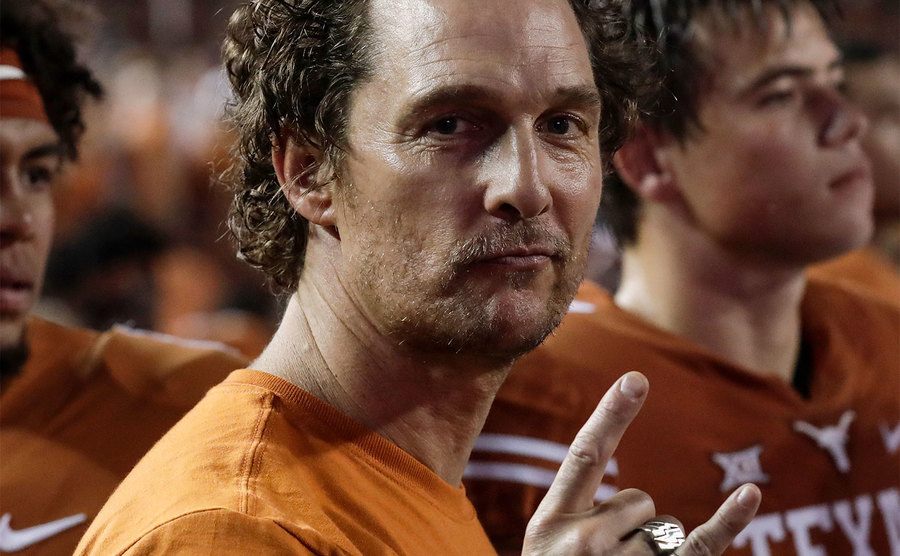 Matthew McConaughey stands on the sideline during a football game.