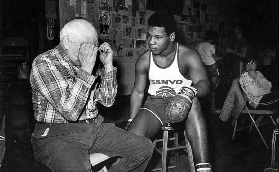 A photo of a young Mike Tyson talking to his boxing coach.