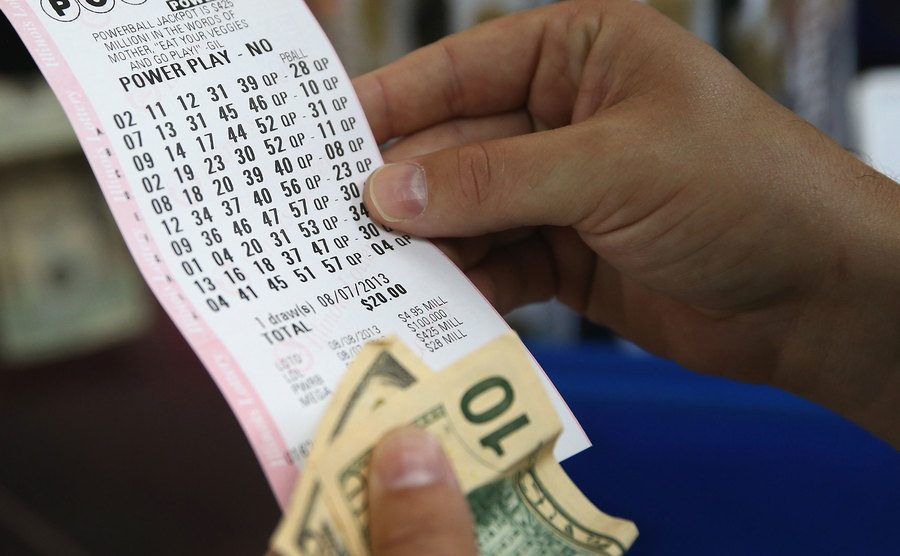 A customer at a 7-Eleven store checks the numbers on his Powerball lottery ticket. 