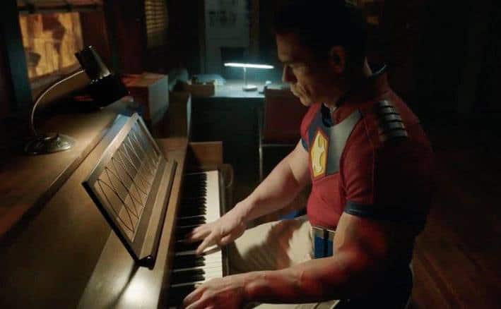 John Cena plays the piano in a still from Peacemaker. 