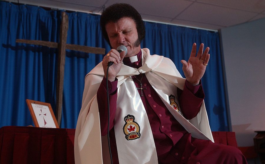 Baxter sings and gestures as Elvis Presley during his sermon.